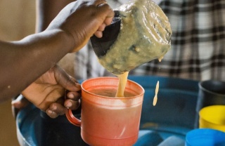 Ein ehrenamtlicher Helfer serviert Porridge in Sambia.