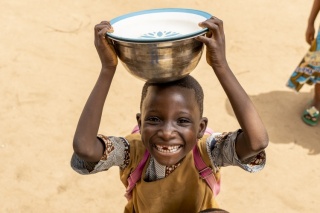 Ein Junge posiert mit einer Schale auf seinem Kopf in Benin.